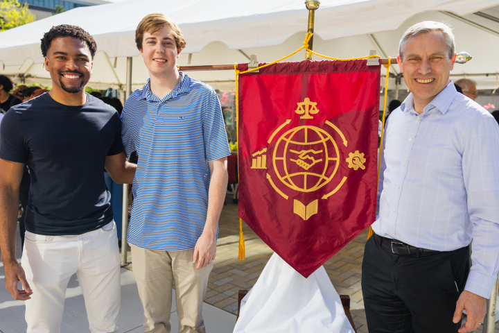 (L to R): Tyler Bonaparte ’25, Patrick Raczka ’25 and ILR Dean Alex Colvin, Ph.D. '99 stand next to the school's new ceremonial banner