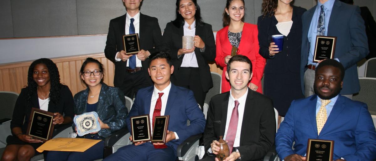 10 members of the Cornell speech team at an awards ceremony with their trophies