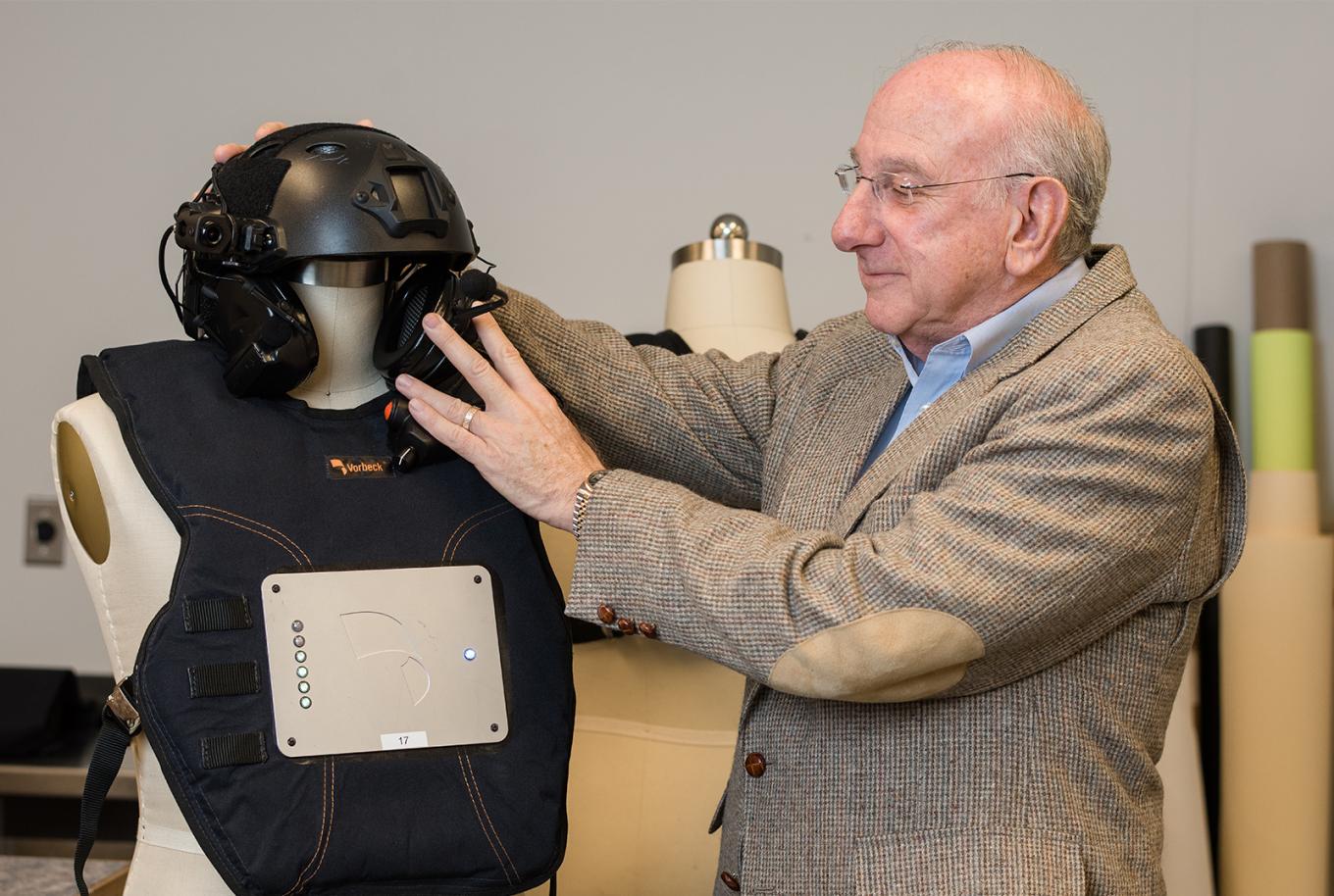 Bill Kilberg ’66 inspects wearable vest and helmet technology with the potential to save lives on mannequin. 