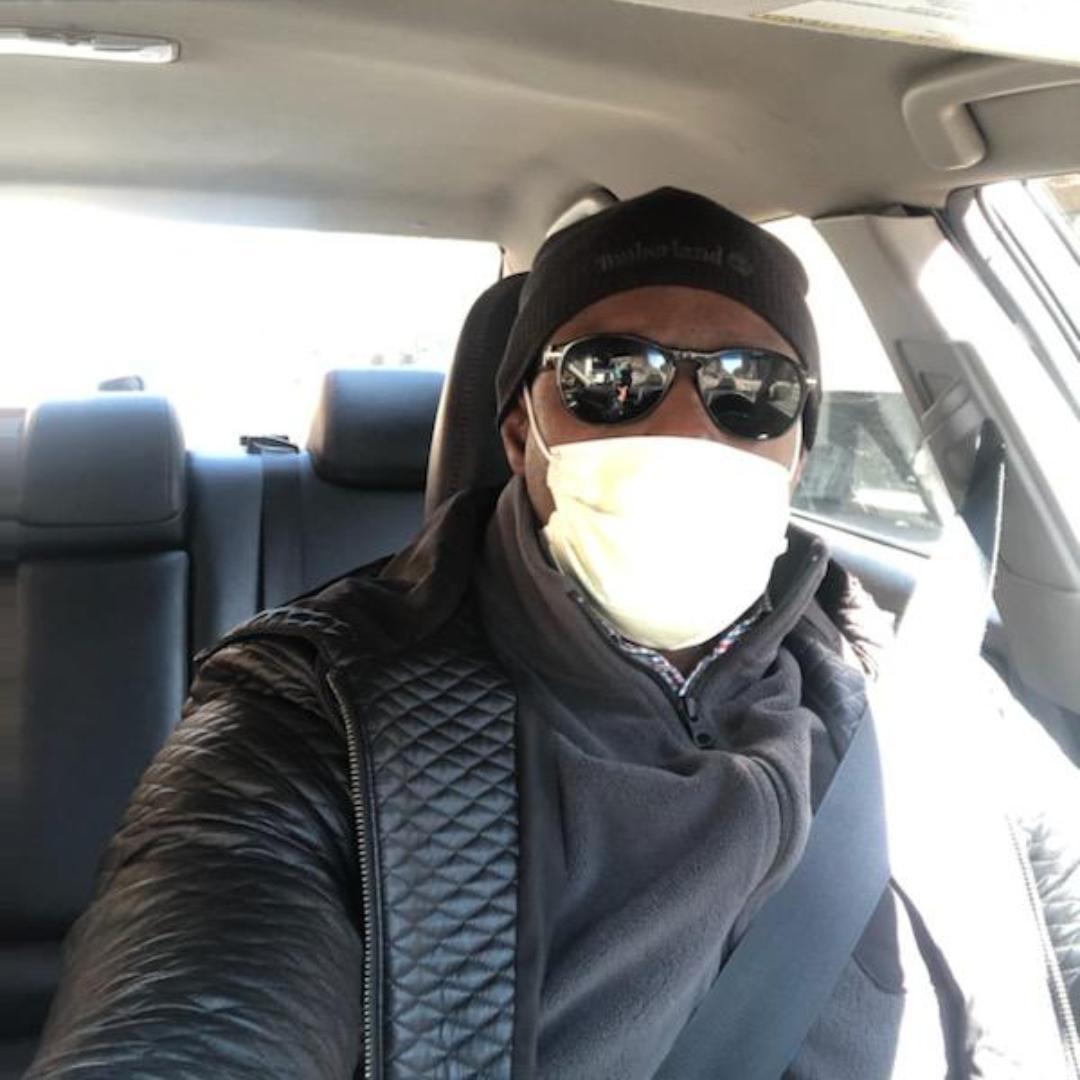 Amara Sanogo driving Lyft/Uber with mask on.