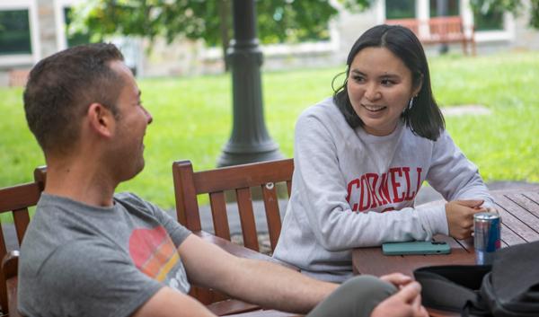 Two EMHRM students sitting and talking at an outdoor table.