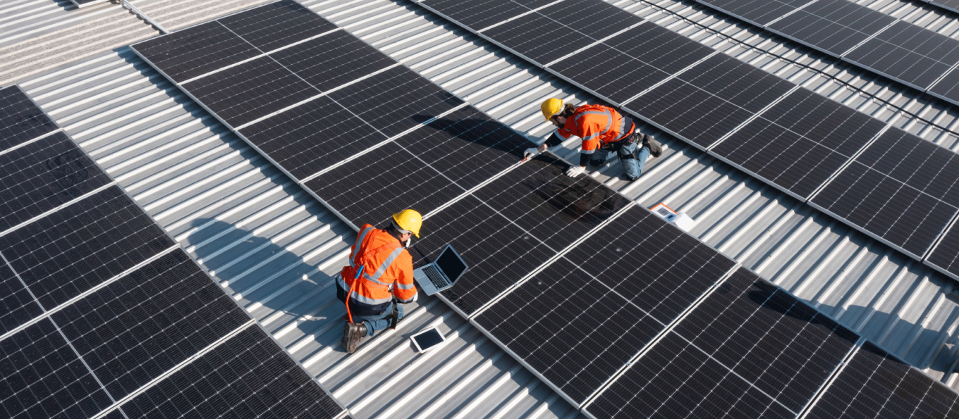 two workers on a roof installing solar panels