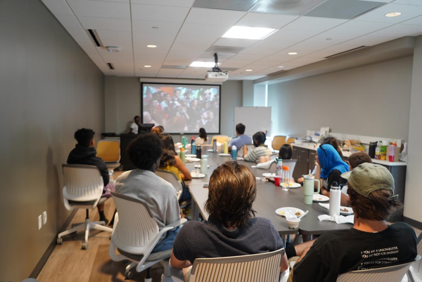 Buffalo High Road students sitting around a table watching a documentary on screen