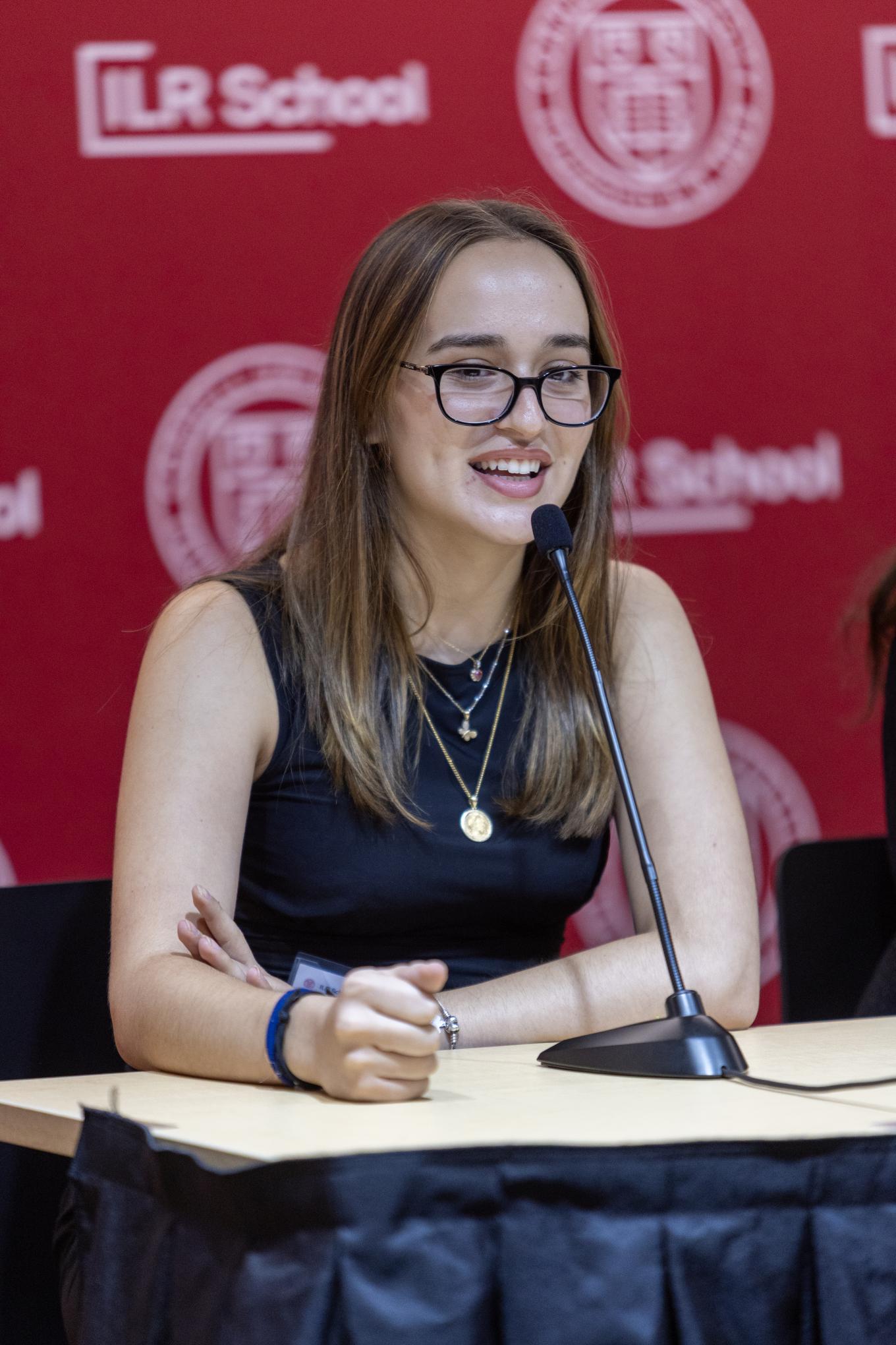 Student sitting while presenting and speaking into microphone