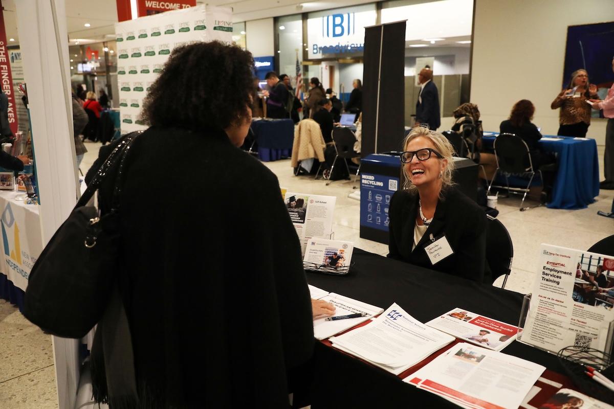 Conference attendee chats with a person who is tabling at a conference