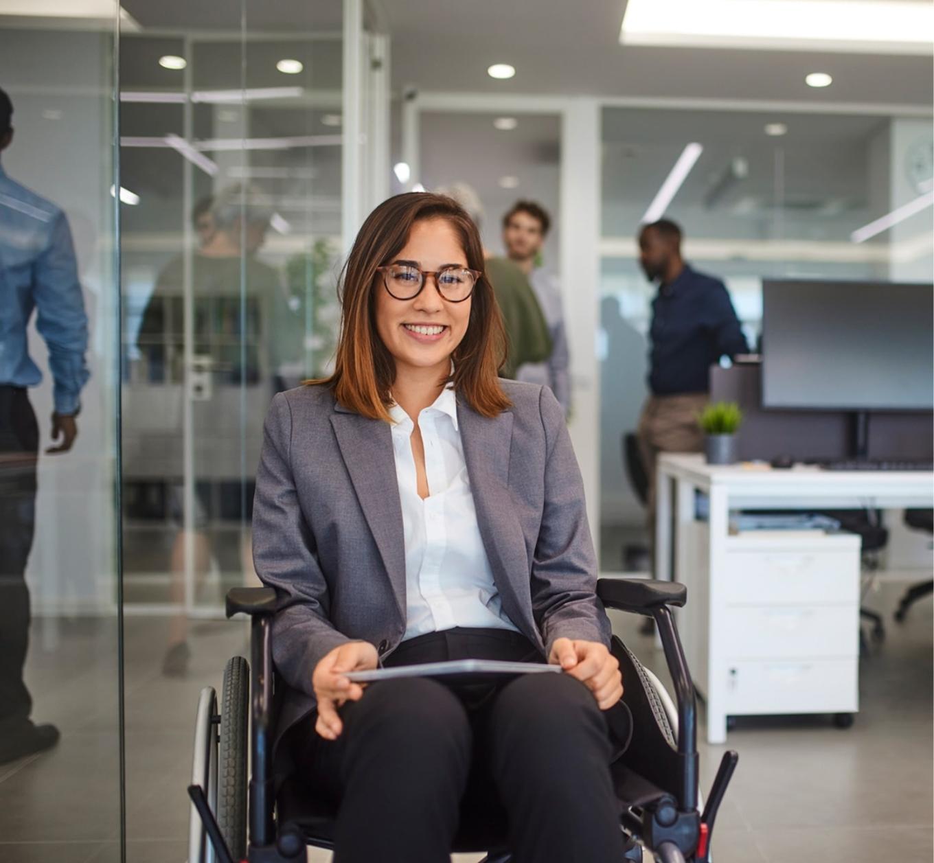 A professionally dressed person at work, using a wheelchair.