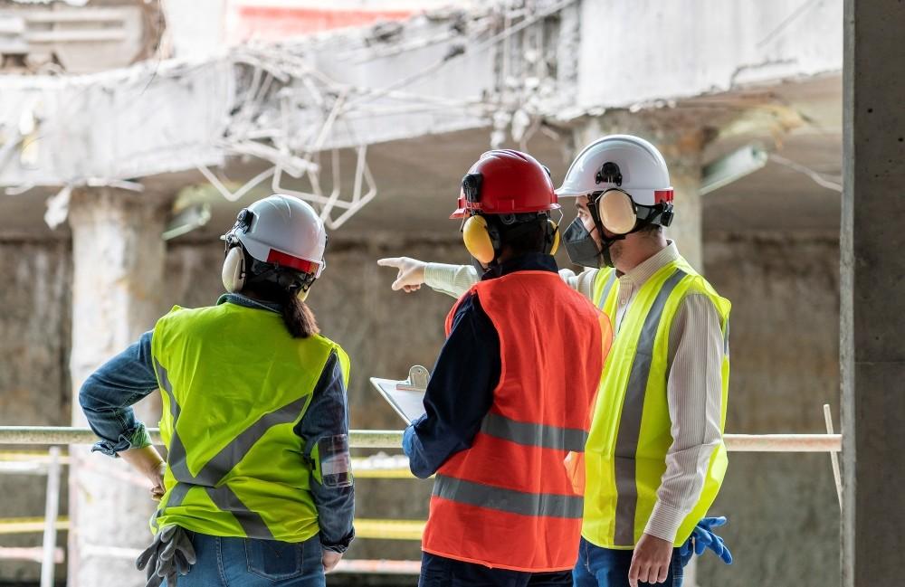 Three construction workers, wearing safety gear