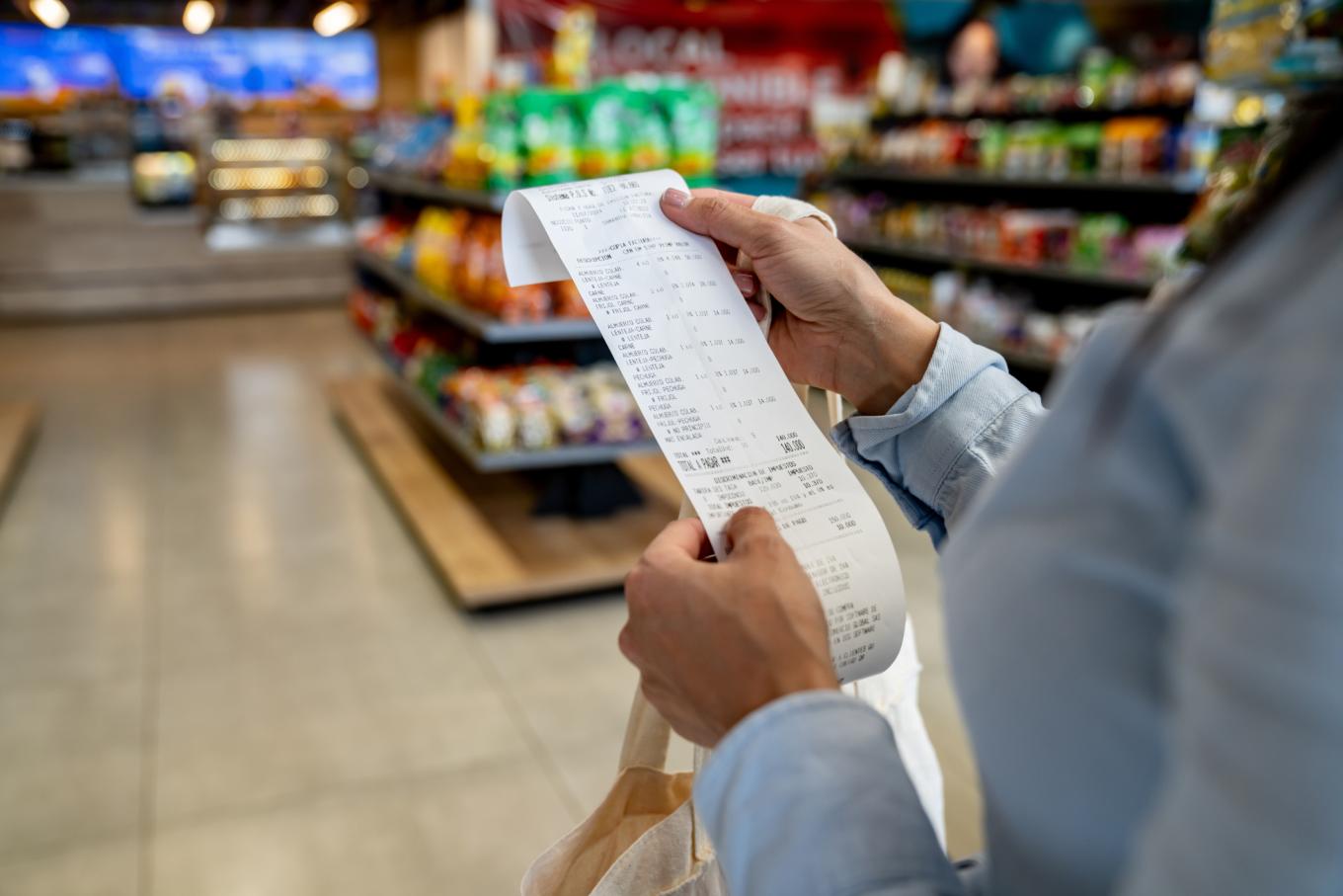 Close-up on a woman shopping at a convenience store and checking her receipt