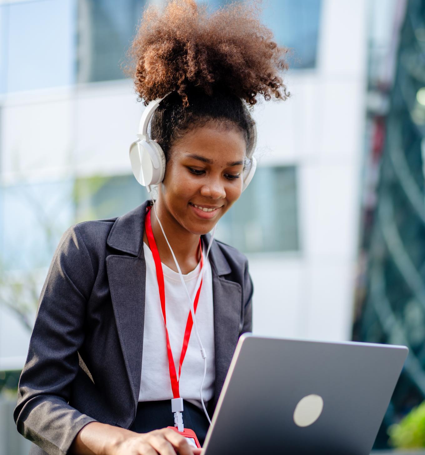 Young businesswoman using a laptop and listening to music working in the park in the city - stock photo