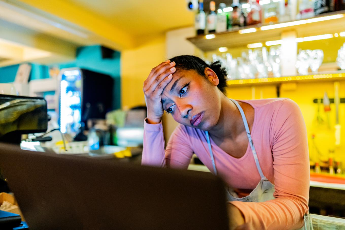Worried young owner using laptop in the coffee shop