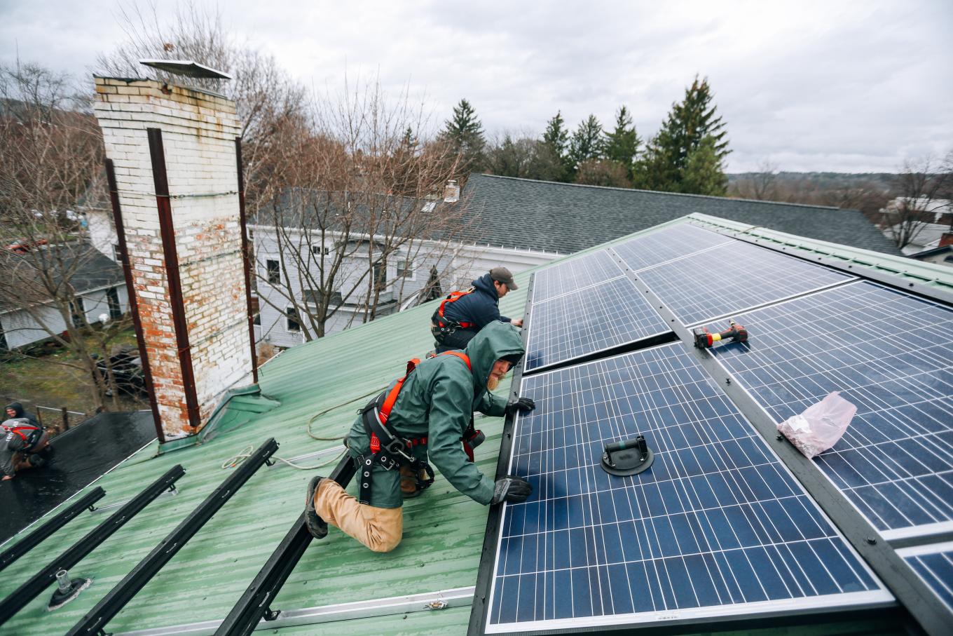 Two men installing solar panels on roof of building