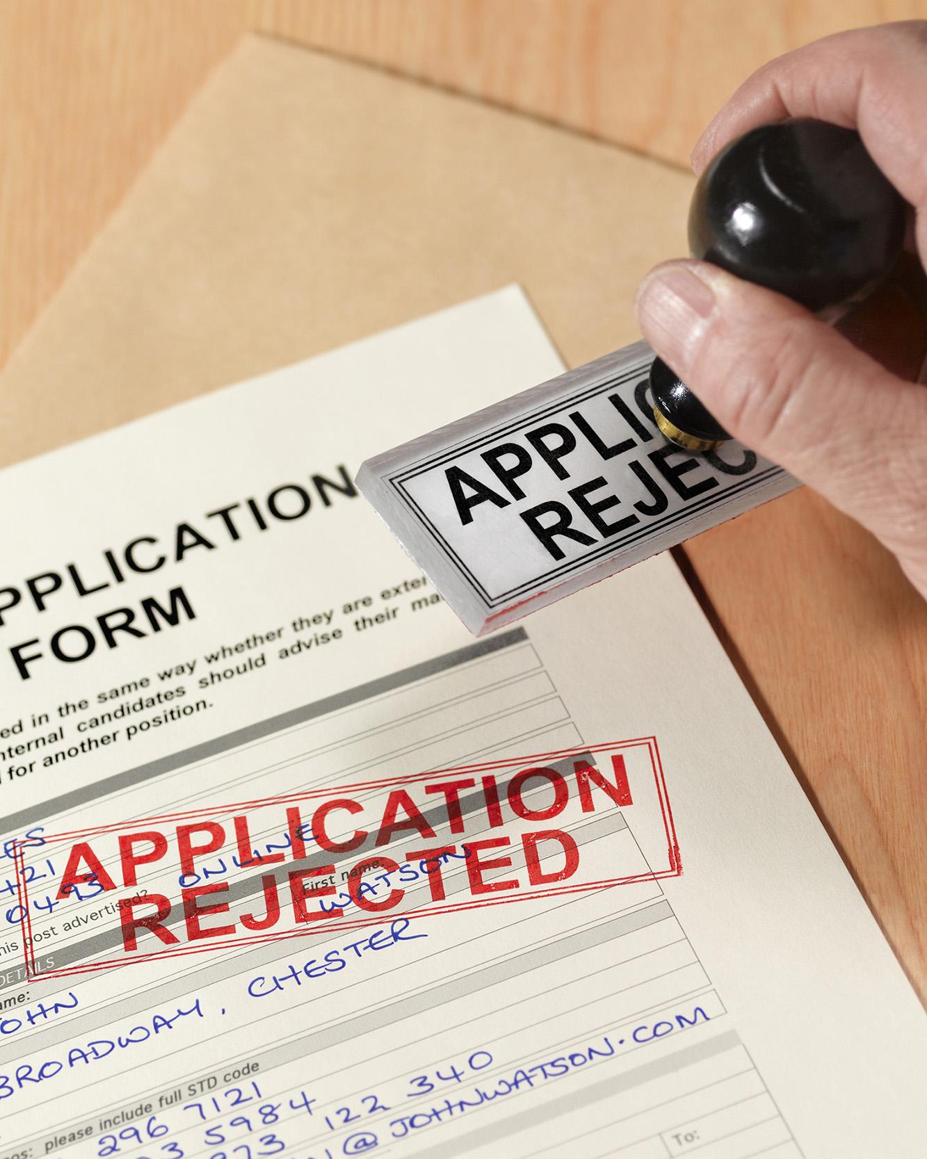 A job application is stamped with “application rejected.