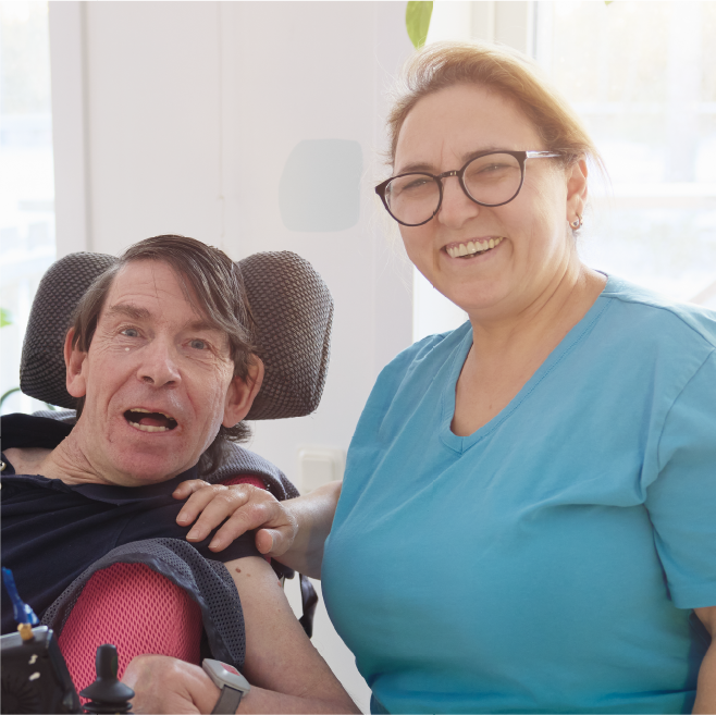 Home care worker standing next to a person in a wheelchair