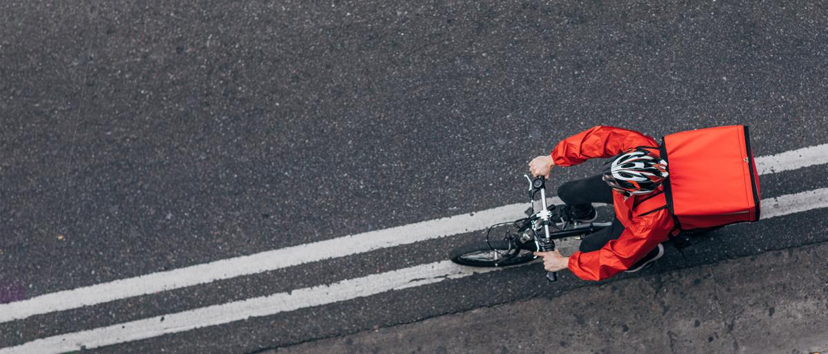 Delivery worker cycling along a paved road