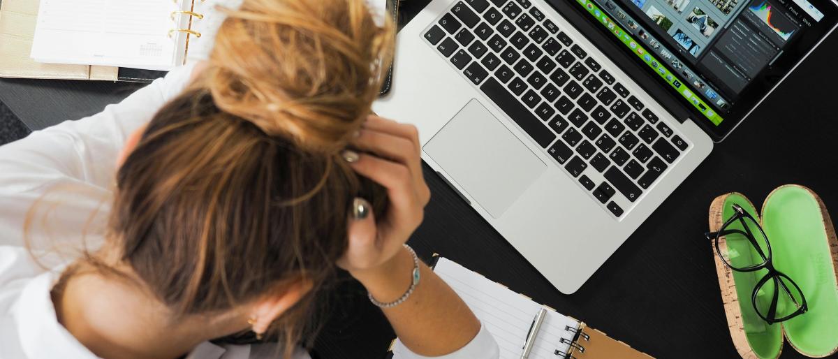 woman sitting in front of macbook with her head in her hands