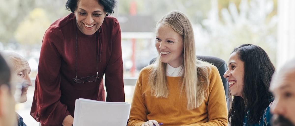 A group of people at an in-person training are reviewing a printed document.
