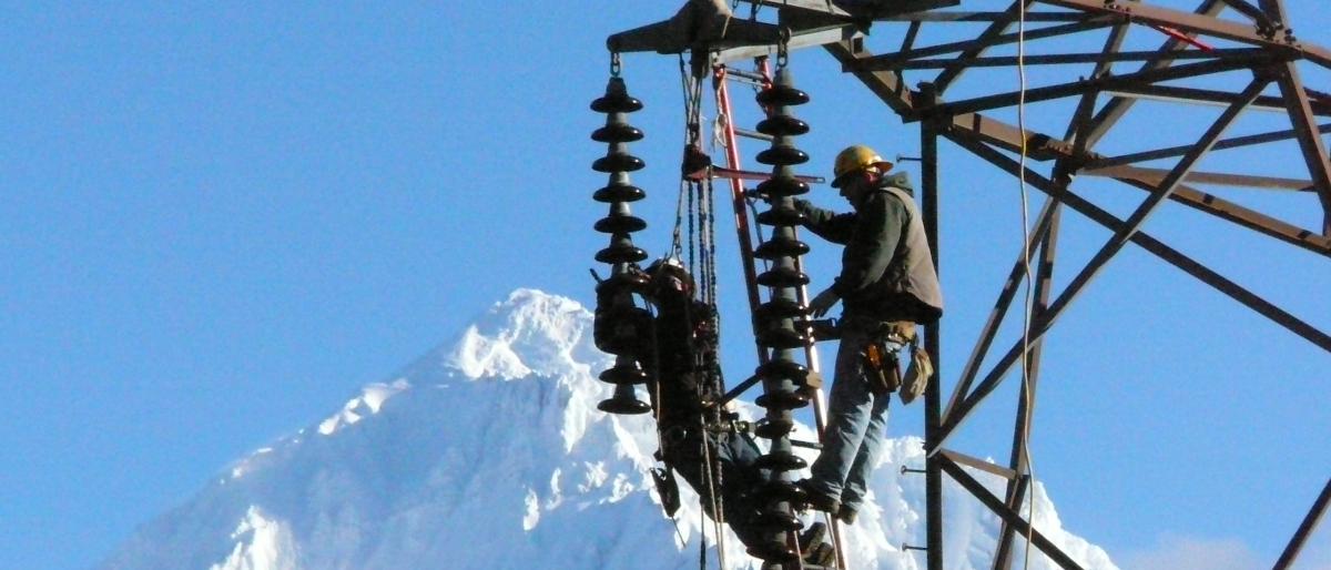 Worker in hard hat working in crane at high altitude with a mountain landscape in the background