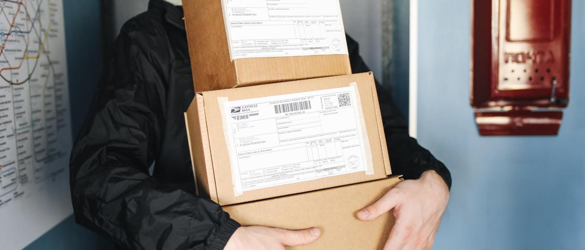 An image with a person carrying a stack of boxes for delivery