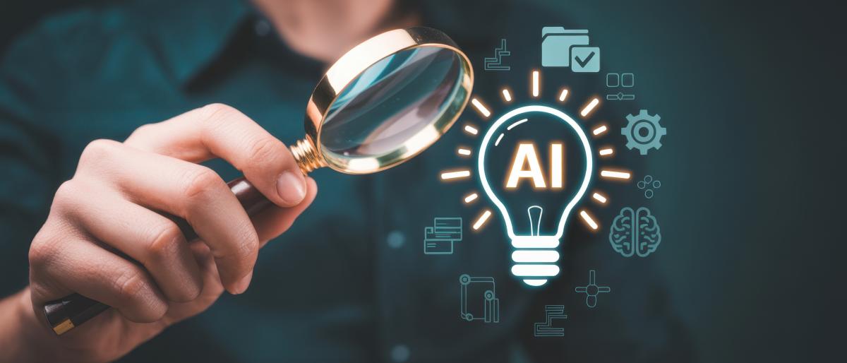 A person uses a magnifying glass to examine a glowing AI lightbulb surrounded by digital business and technology icons.