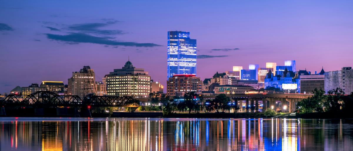 city buildings and lights reflected in a river at dusk