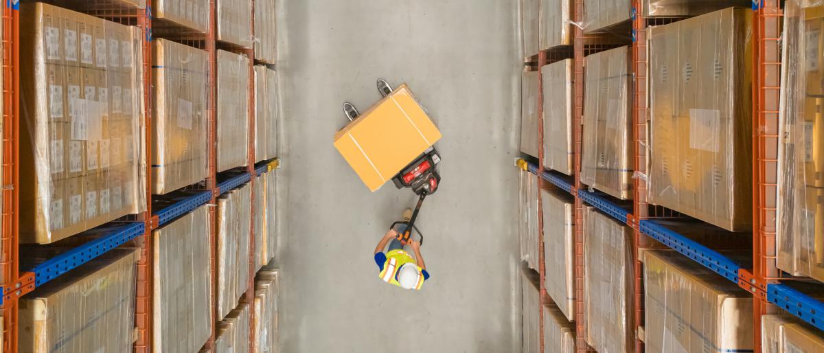 overhead shot of warehouse worker pushing boxes with surrounding shelves of packages