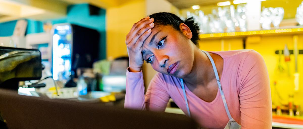 Worried young owner using laptop in the coffee shop