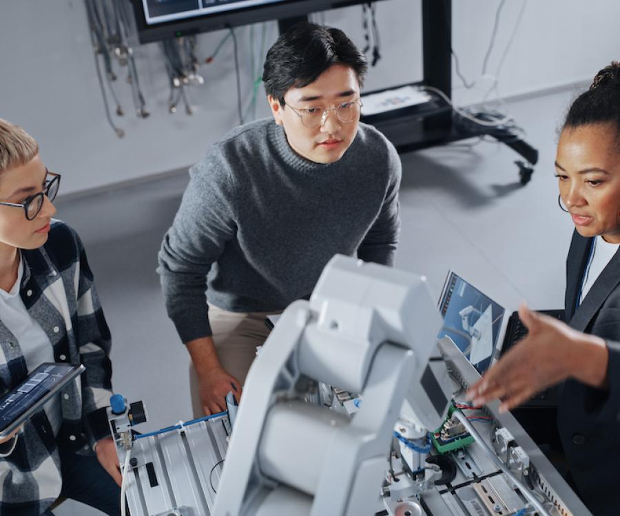 Three workers seated around a high-tech machine