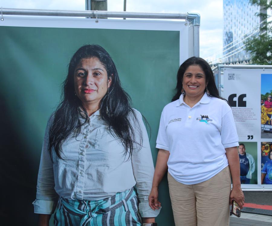 Woman in a white polo standing in front of exhibit image of herself
