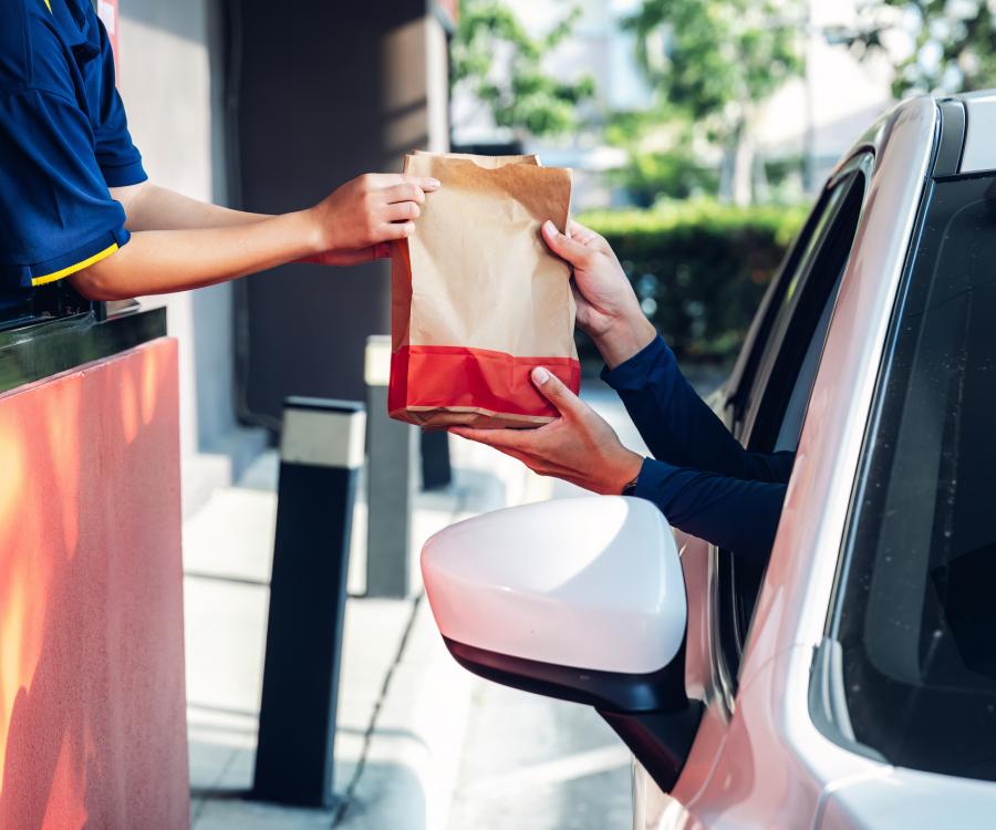 Staff serving takeaway order for driver in delivery window