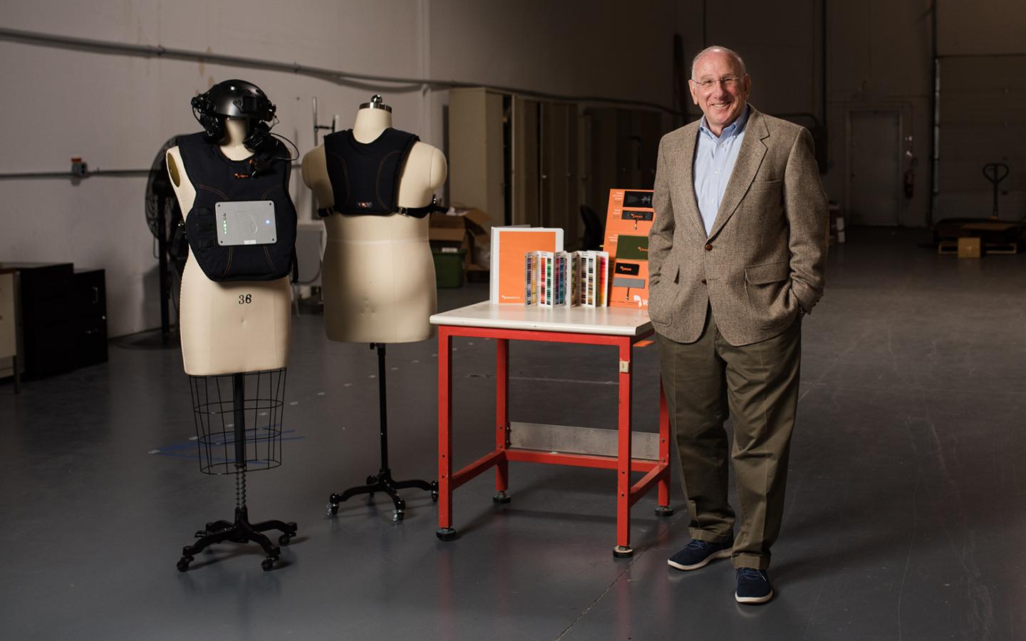 Bill Kilberg ’66 standing next to mannequins donned in wearable technology with the potential to save lives. Technology includes vests and helmets.