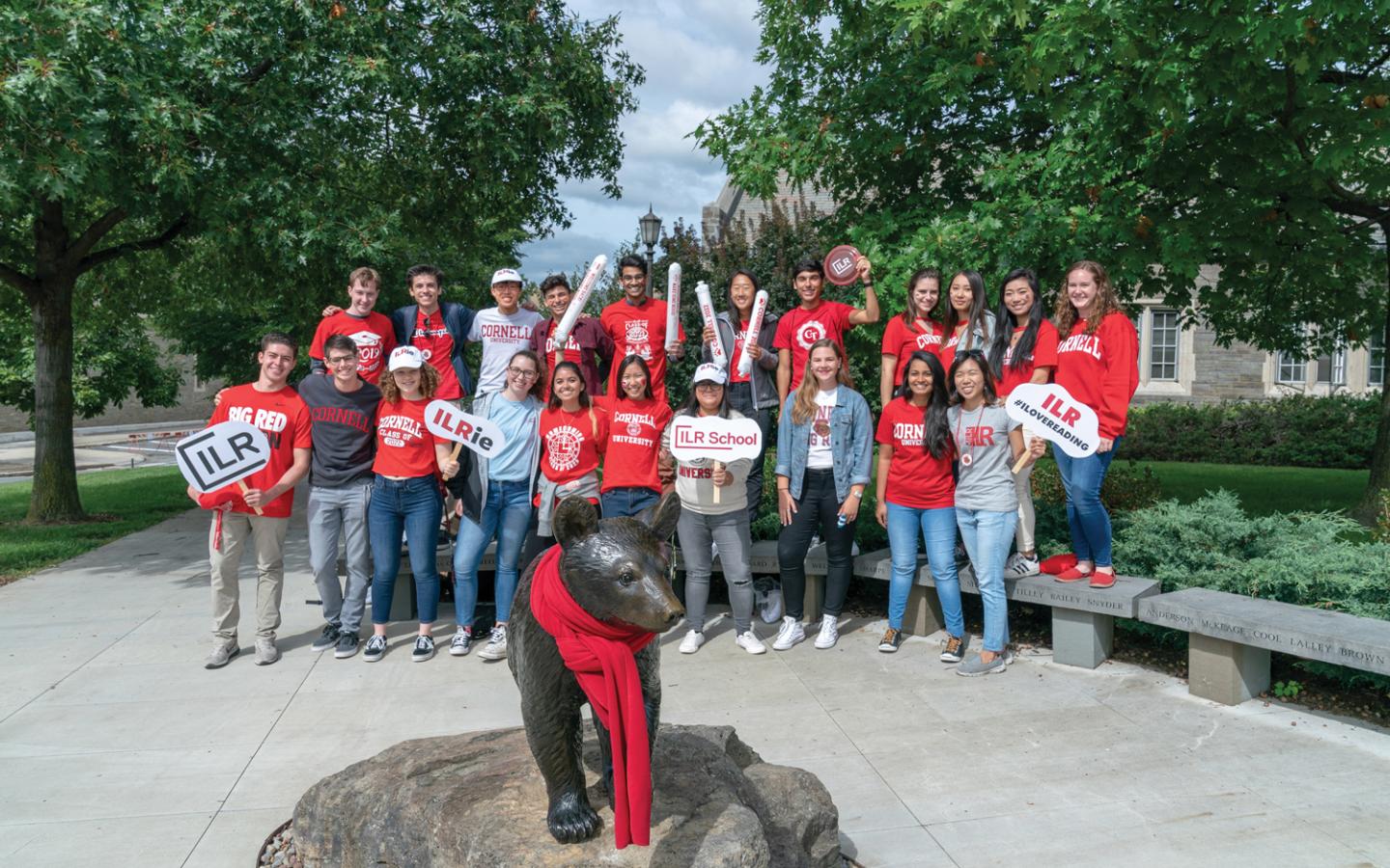 Large group of ILR students posing by Touchdown the Bear statue during Cornell Homecoming.