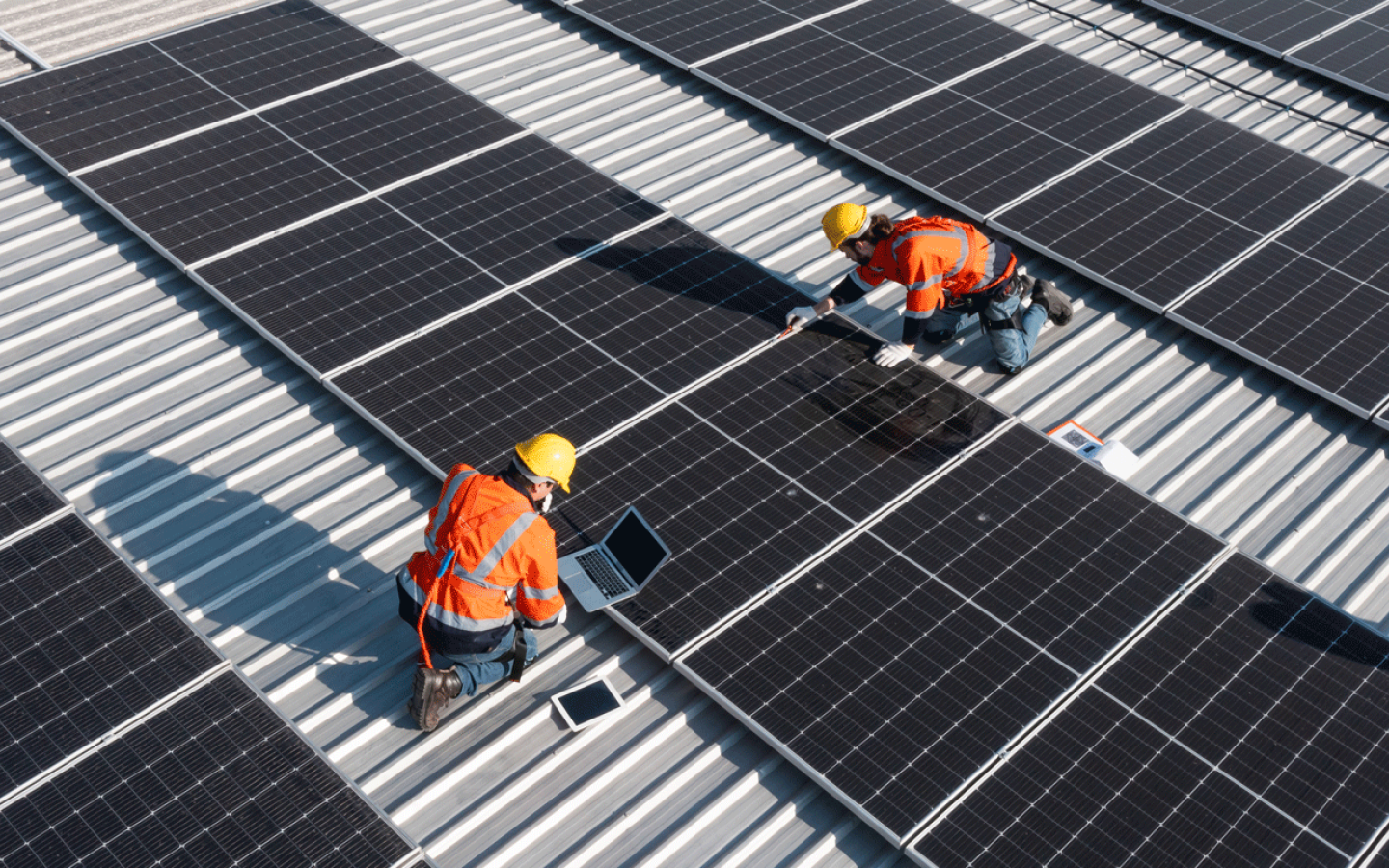 two workers on a roof installing solar panels