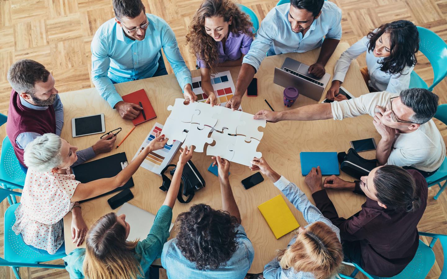Group of co-workers putting a puzzle together across the table