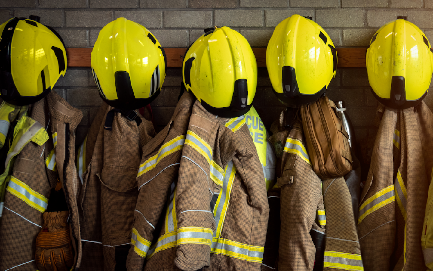 Firefighters' helmets and jackets hung on a row of hooks