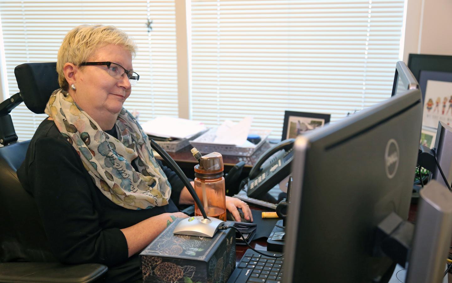 woman in a wheelchair working on a computer in her home office