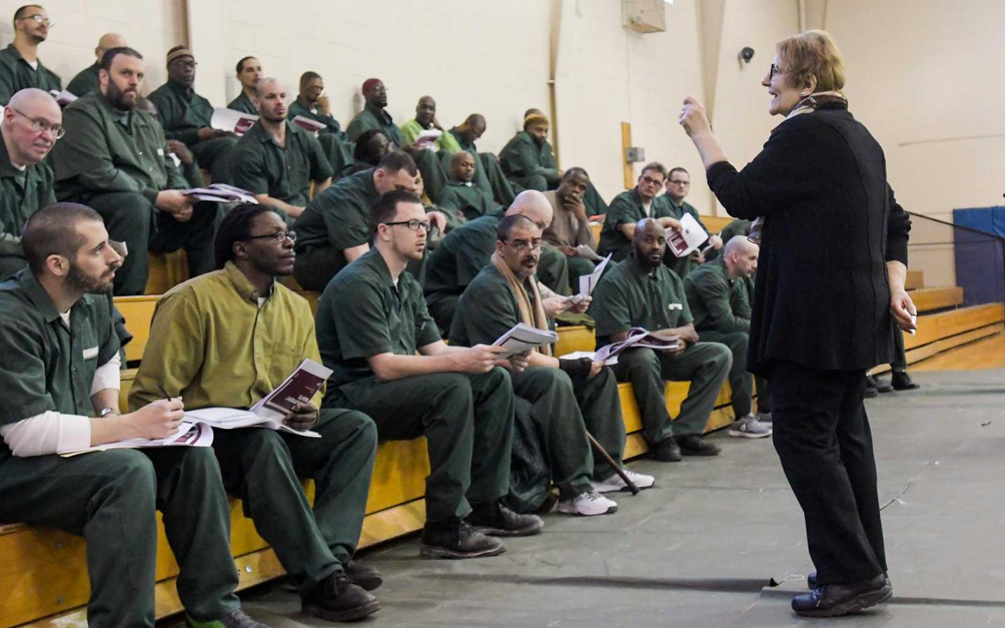 Esta Bigler speaks to inmates seated on bleachers at Cayuga Correctional facility