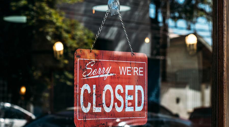 "Sorry, we're closed" sign hanging on a business door.