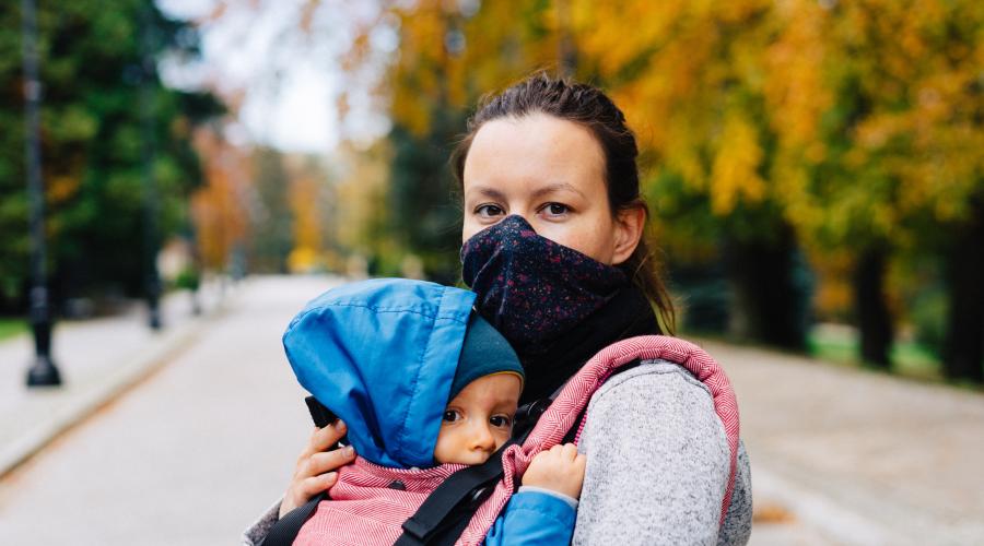 Photo of masked woman carrying a child by Marcin Jozwiak on Unsplash