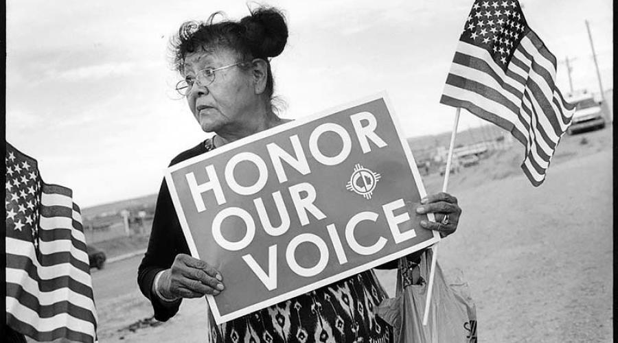 Woman holds a sign reading "Honor Our Voice"