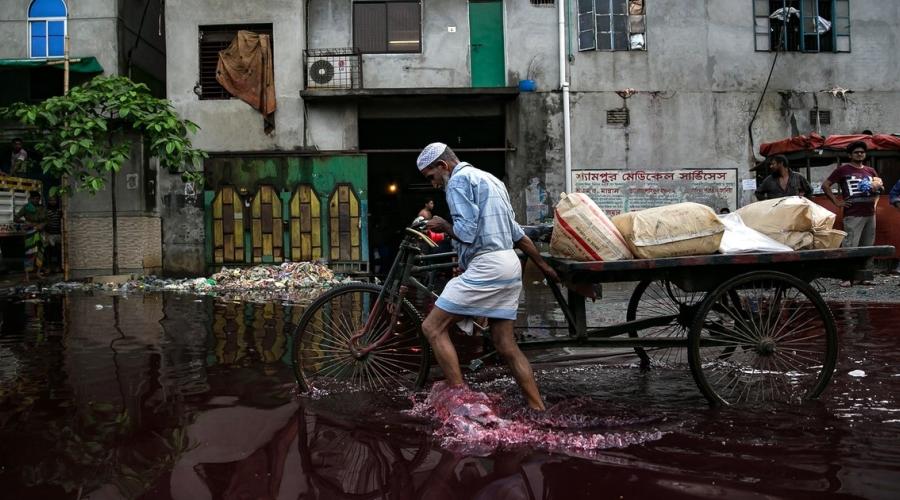 A man walks through rain and dye outside a dyeing factory in Bangladesh. (Getty)