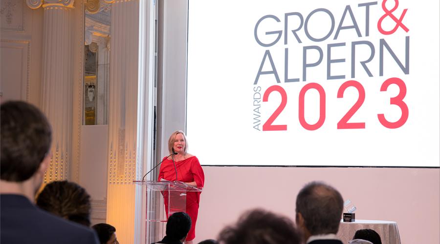 Christy Pambianchi speaking at a lectern on stage at the Groat and Alpern awards.