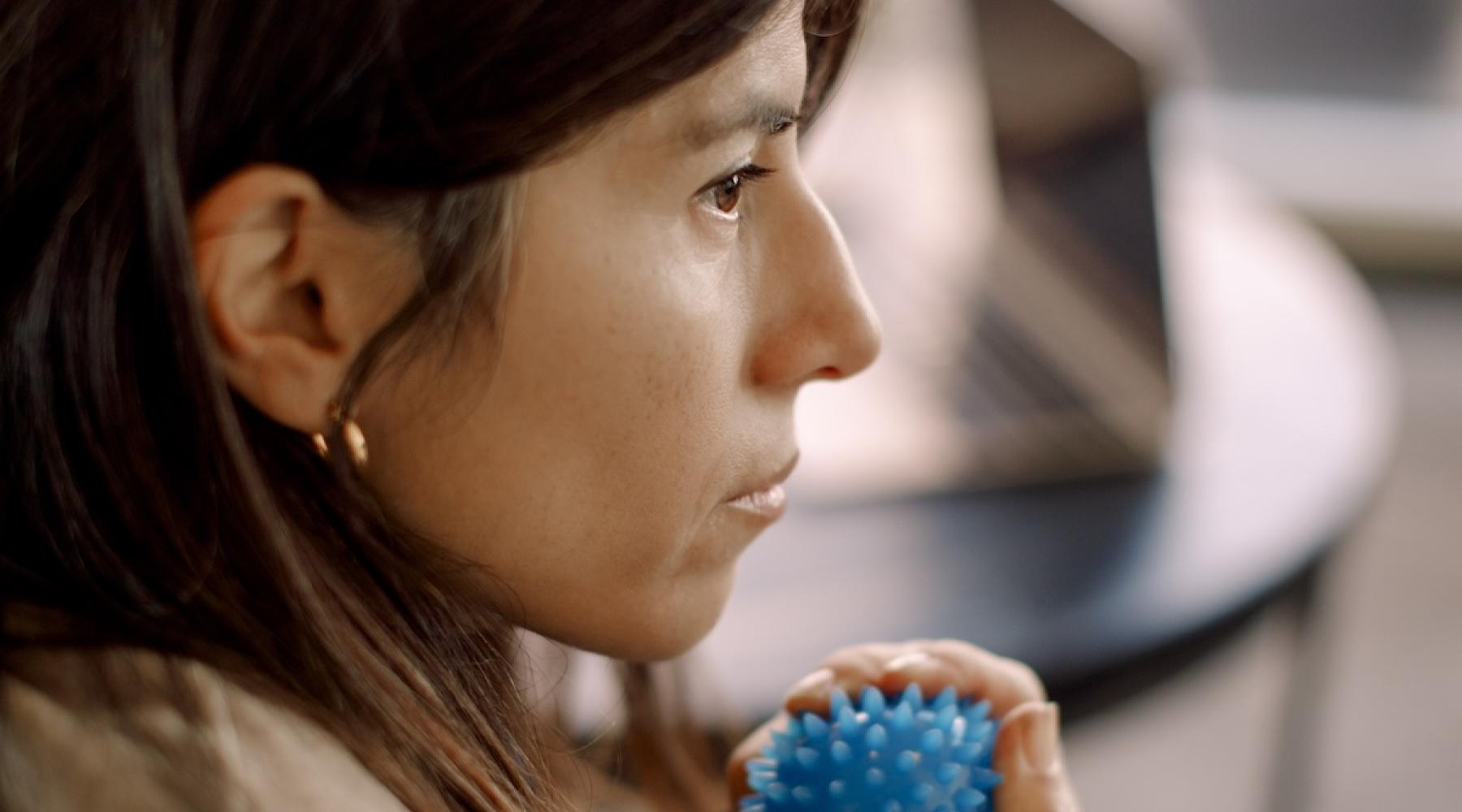 A person squeezes a small blue stress/massage ball