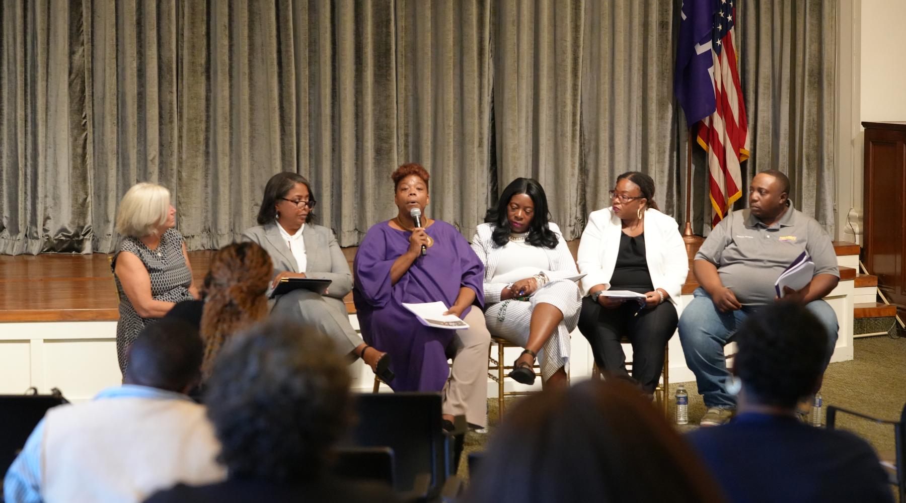 5 panelists and moderator sit