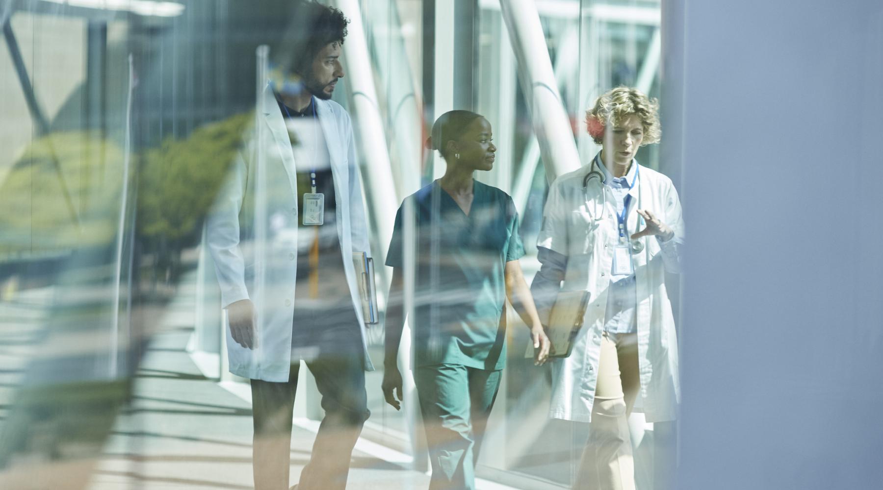 Three doctors: one man, two woman walking and talking 
