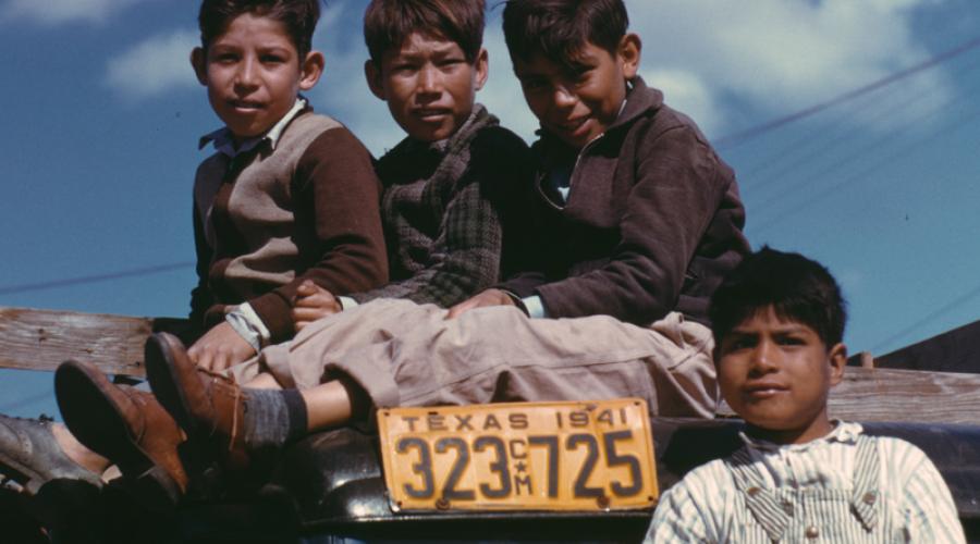 Boys sit on a truck at the Farm Security Administration’s Migratory Labor Camp in Robstown, Texas