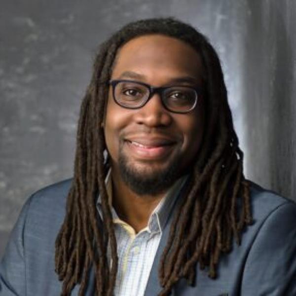 professional man smiles at camera with grey suit coat and white shirt