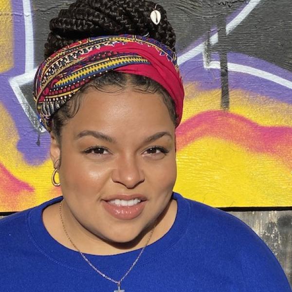 professional woman smiles at camera in front of mural