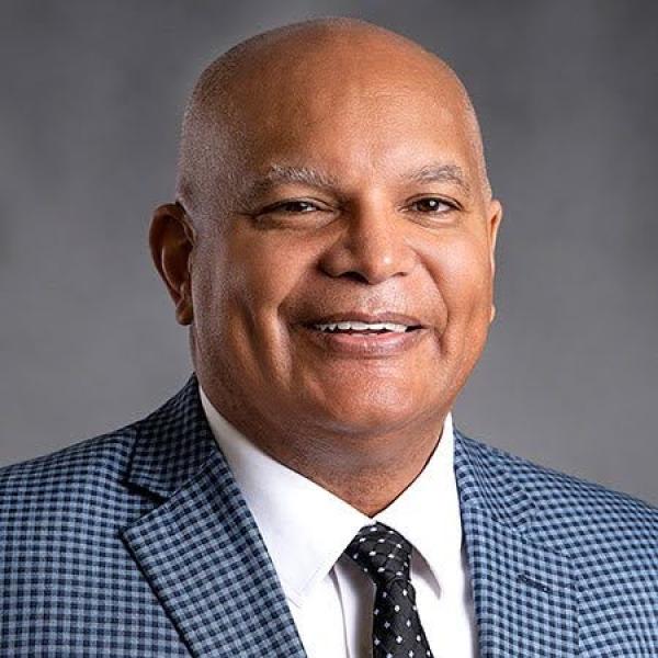 man in suit jacket and tie smiles at camera