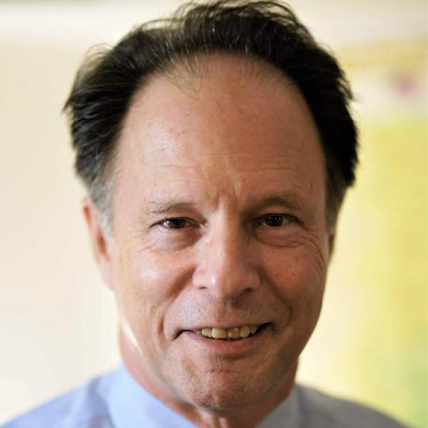 man in button shirt and tie smiles at camera