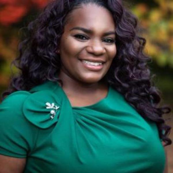 Professional woman in green shirt smiles at camera
